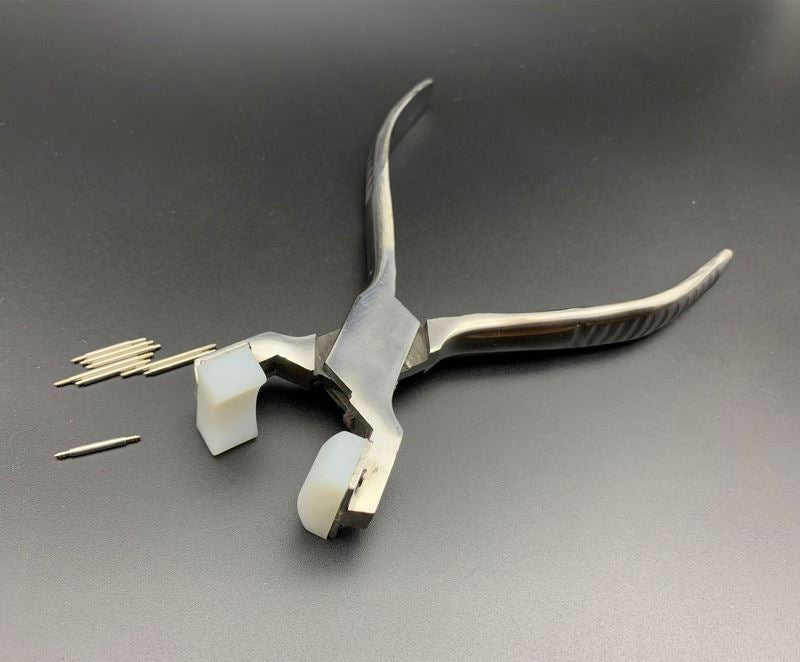 Spring shaft pliers for watchband adjustment with steel bracelet and connecting ear rod.