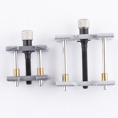Metal watchmaker clamp and movement holder tool set for precise watch case repairs.