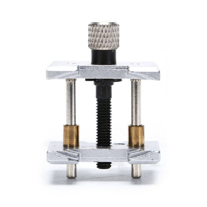 Metal watchmaker clamp and movement holder tool set for precise watch case repairs.